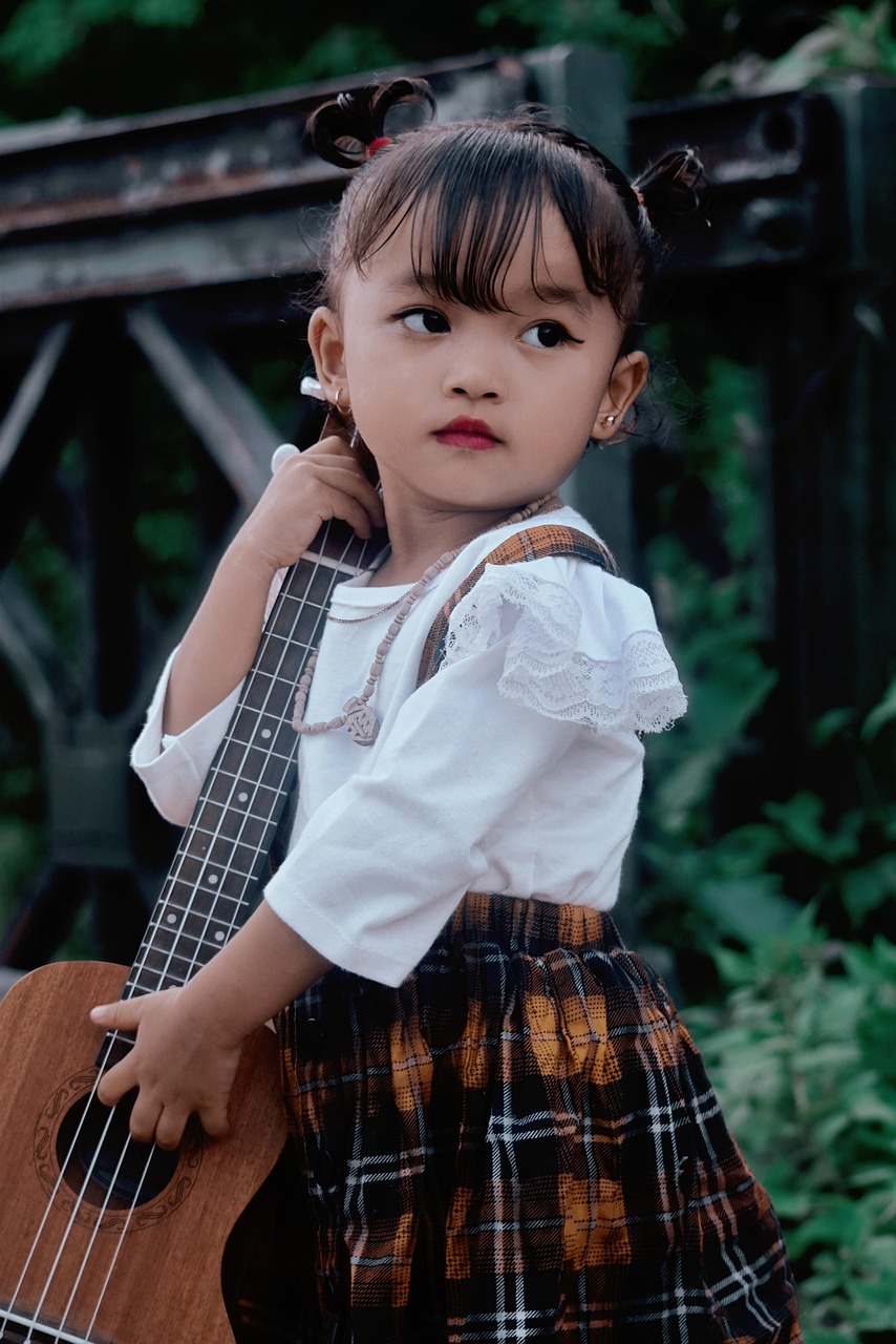 Child holding a ukulele, ready to play an easy song
