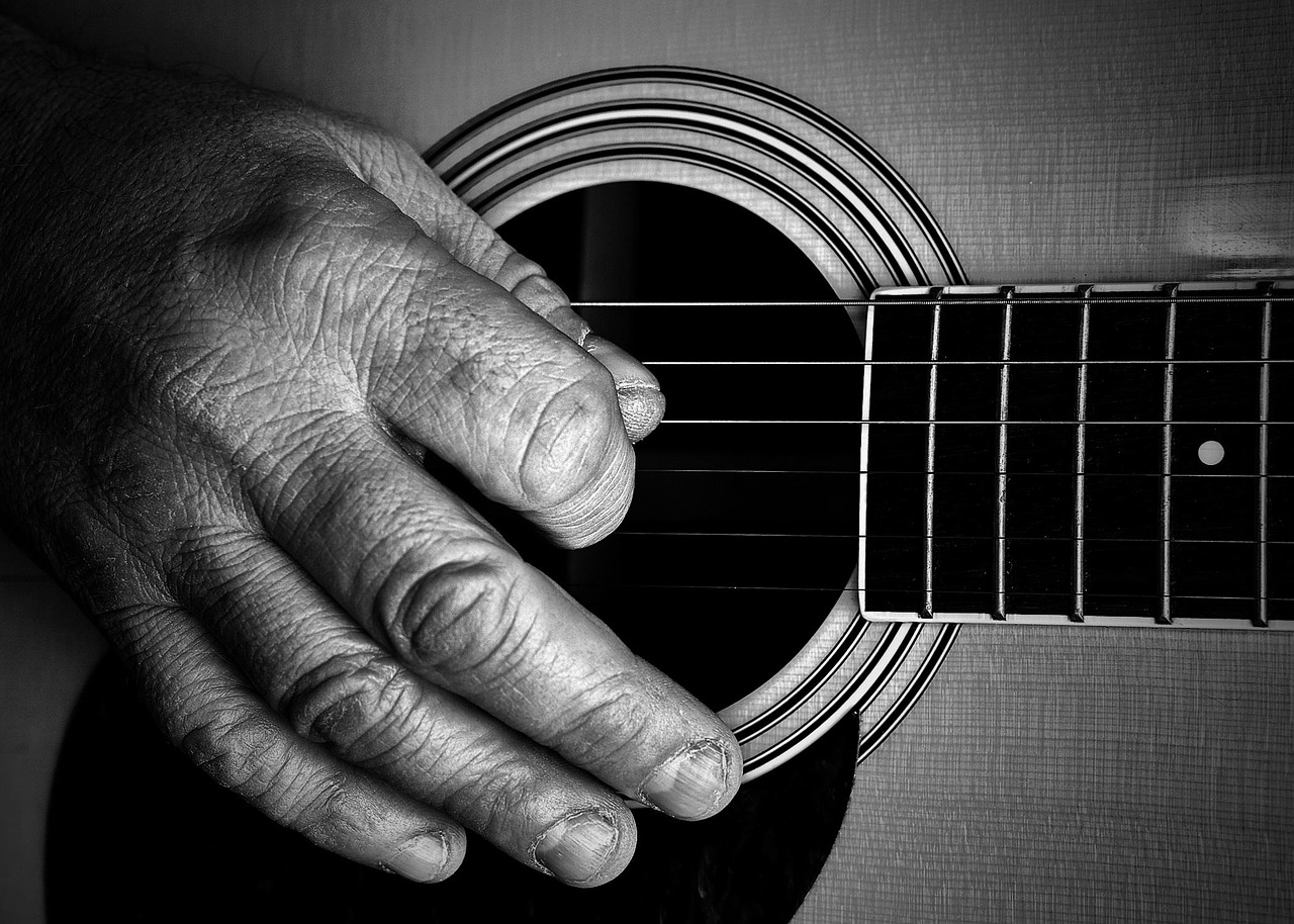 Fingerpicking hand over the sound hole of an acoustic guitar