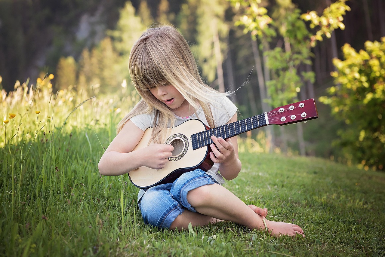 Young child playing an easy song on a small acoustic guitar