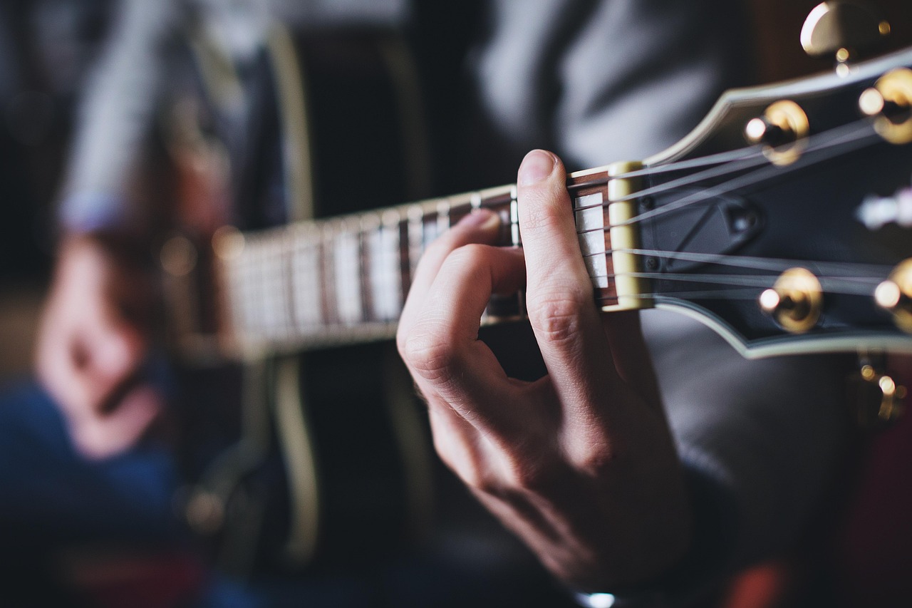 Guitarist fretting a three-chord progression on guitar